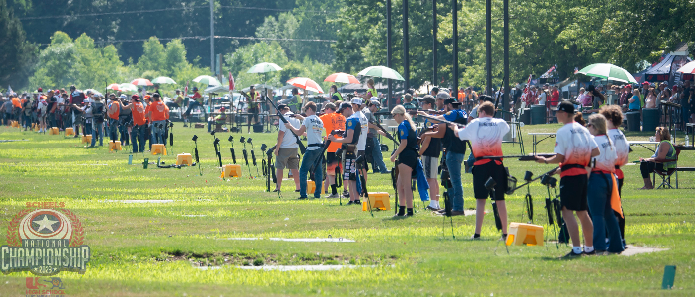 A group of people are lined up in a field ready to shoot.